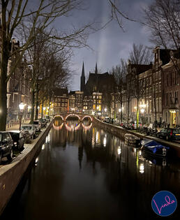 Amsterdam canal at night with lights reflecting in the water