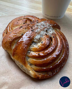 cardamon bun on a napkin next to a cup of coffee